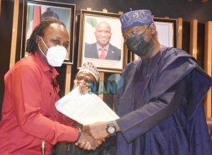 Victor Ekpeba being presented his CoOby the Minister of Works and Housing, Babatunde Fashola